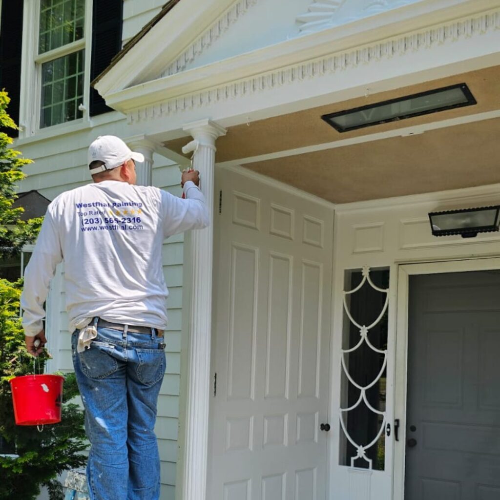 A professional house painters from Westfhal Painting & Drywall LLC meticulously painting the front entrance of a Connecticut home.