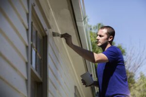 A professional house painters meticulously painting the exterior of a house in Connecticut.