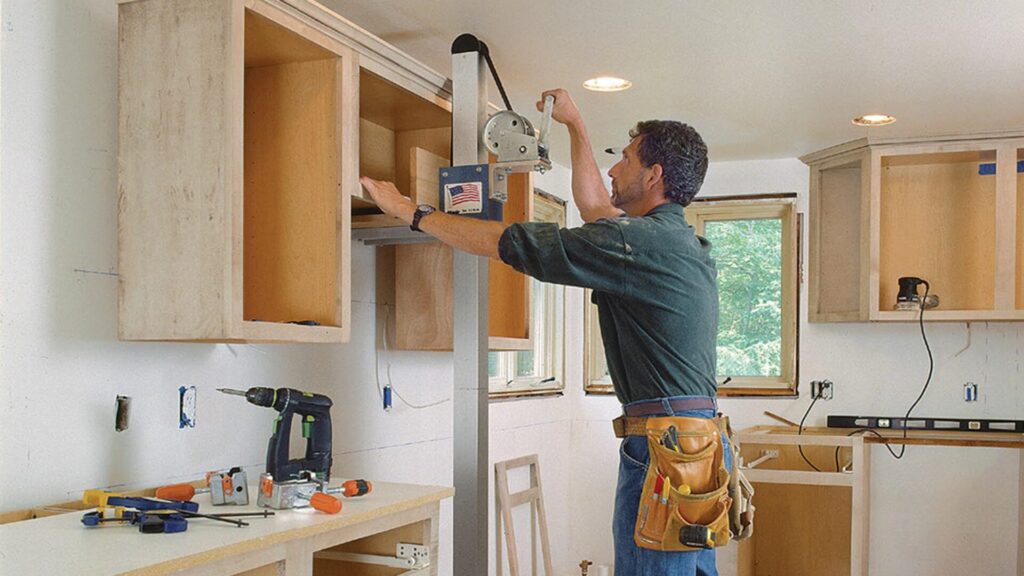 A professional carpenter installing a kitchen cabinet.