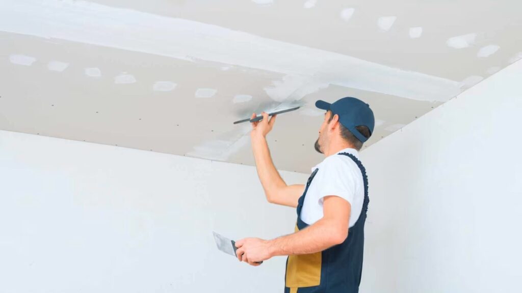 A professional carpenter repairing drywall on the ceiling in a residential home.