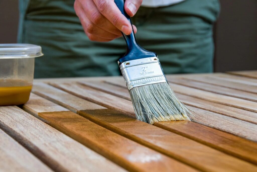 Man applying wood stain to deck for a professional finish.